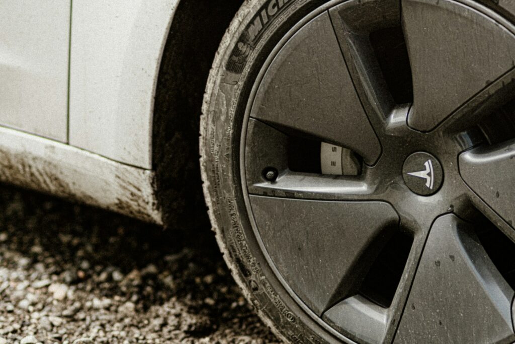 Nærbillede af et hjul med Tesla-logo og dæk på en hvid Tesla Model 3