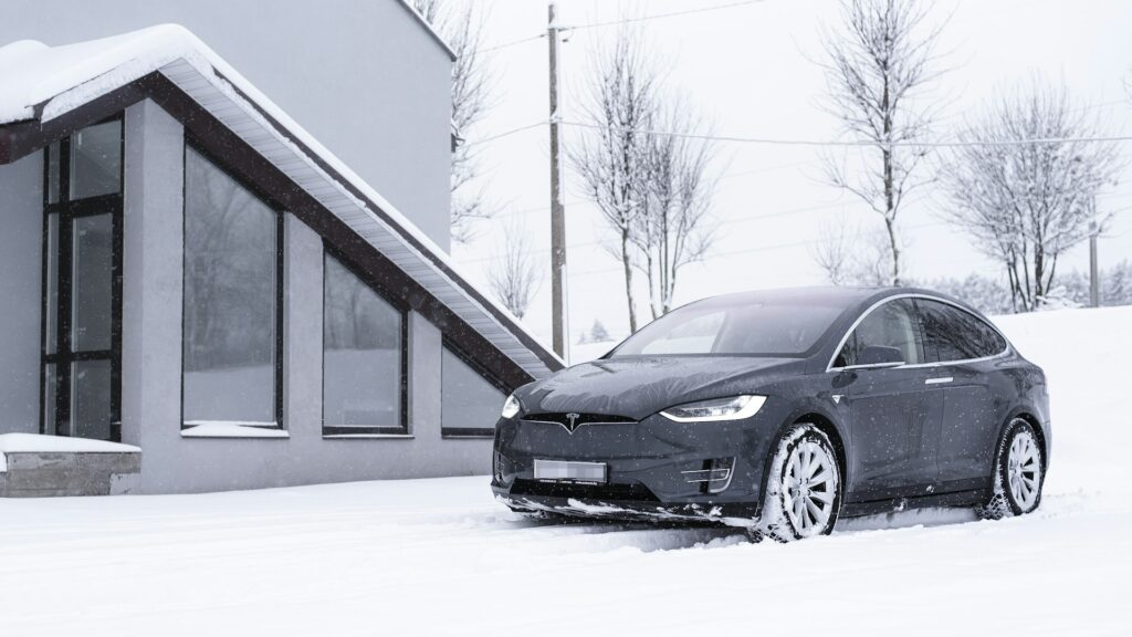 Mørkegrå Tesla Model X parkeret i sne foran et hus