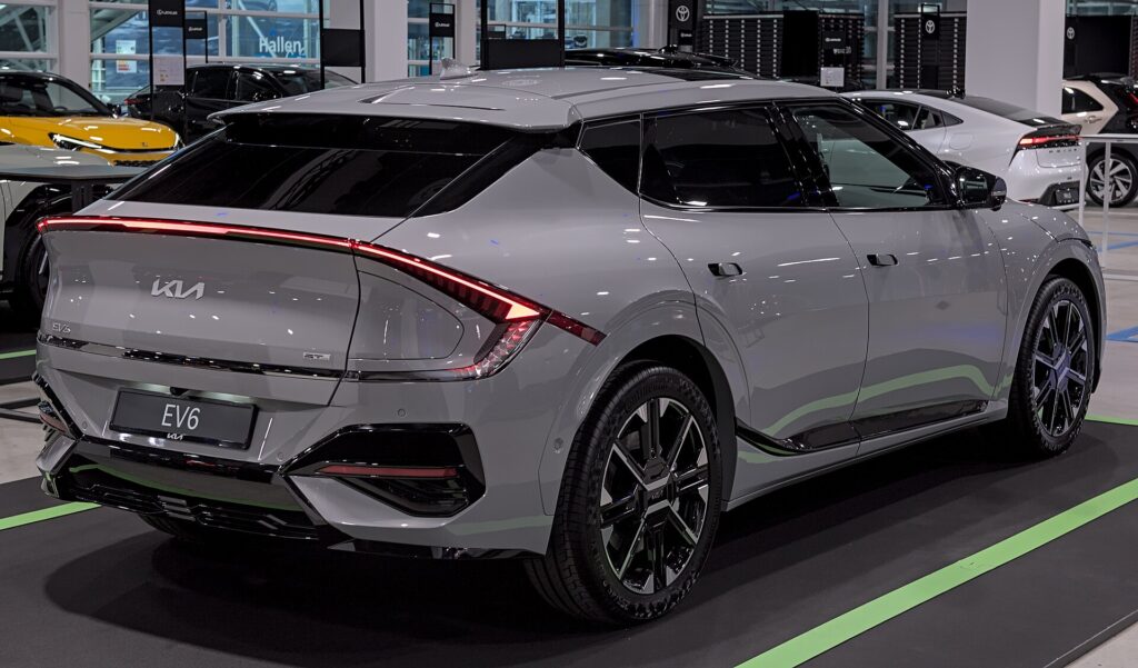 Grå Kia EV6 GT-Line efter faceliftet set skråt bagfra i et udstillingslokale