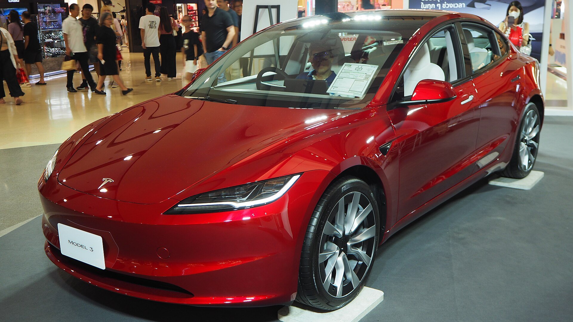 Rød Tesla Model 3 af den nyeste generation udstillet i et showroom