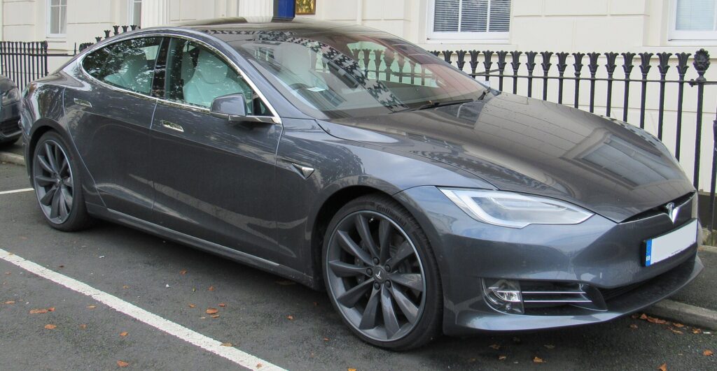 Grå Tesla Model S 90D fra 2017 parkeret ved et sort jerngelænder