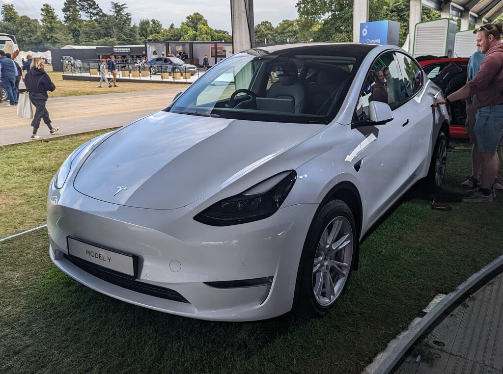 Hvid Tesla Model Y fra 2022 udstillet på græs ved et udendørs arrangement