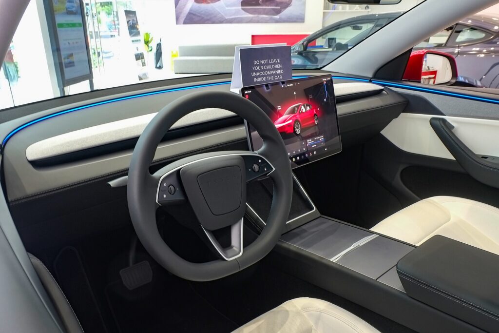 Kabine i en Tesla Model Y af den nye generation med rat og den store midterskærm