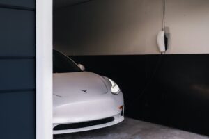 Hvid Tesla Model 3 parkeret i en garage med en Tesla Wall Connector på væggen